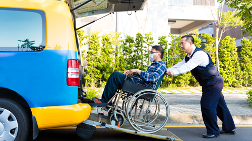 Man helping passenger on wheelchair getting on vehicle